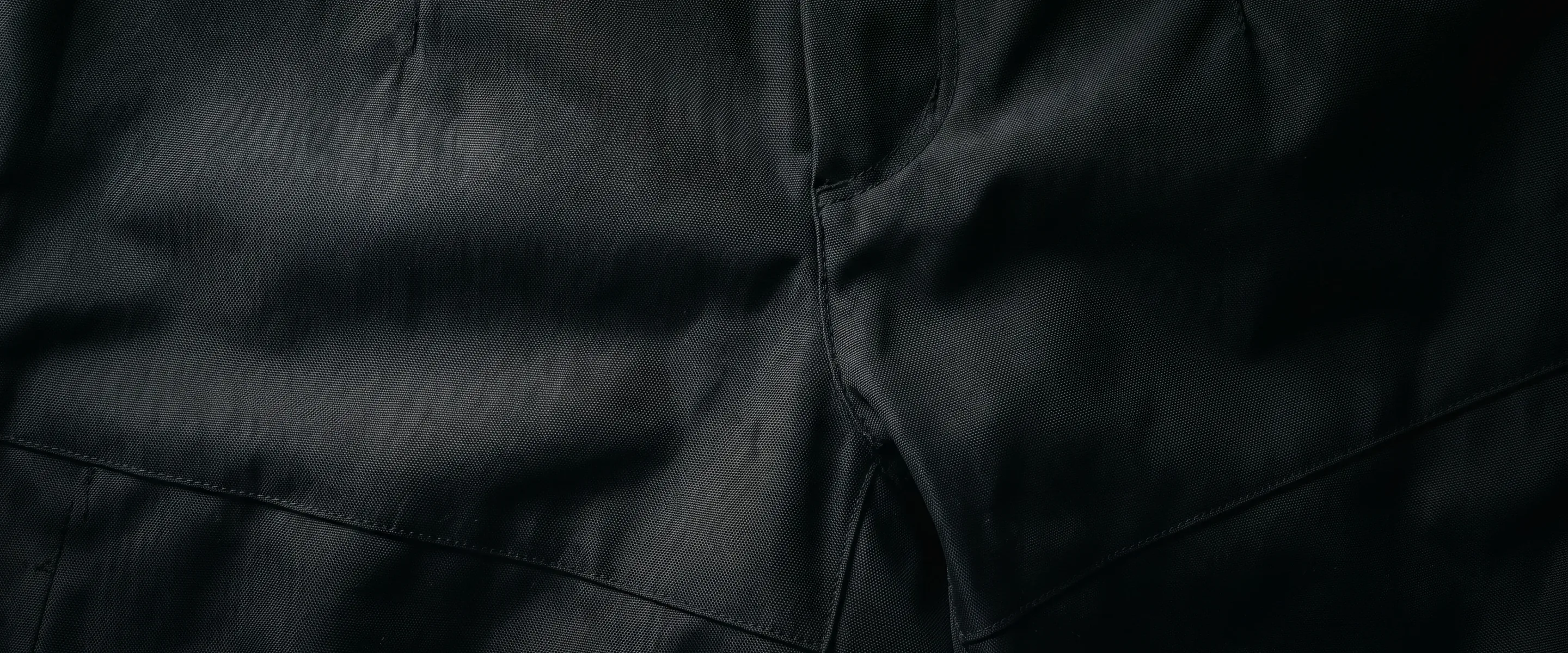 Full-bleed near-black woven cloth in raking light