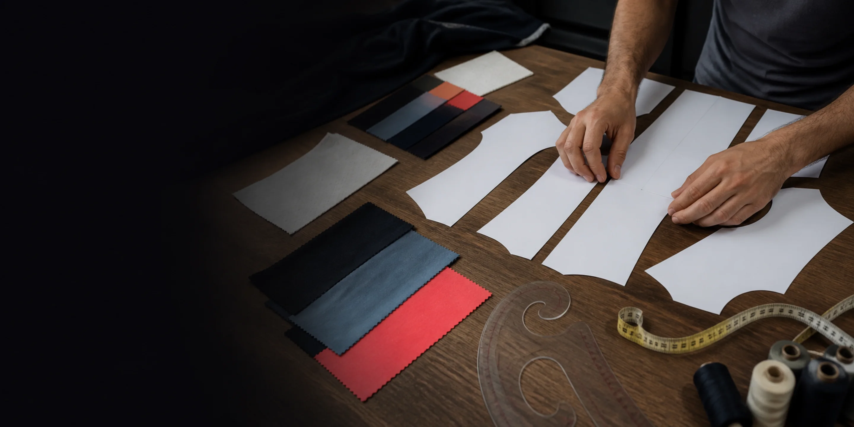Pattern pieces, fabric swatches and a tape measure laid out on a development table