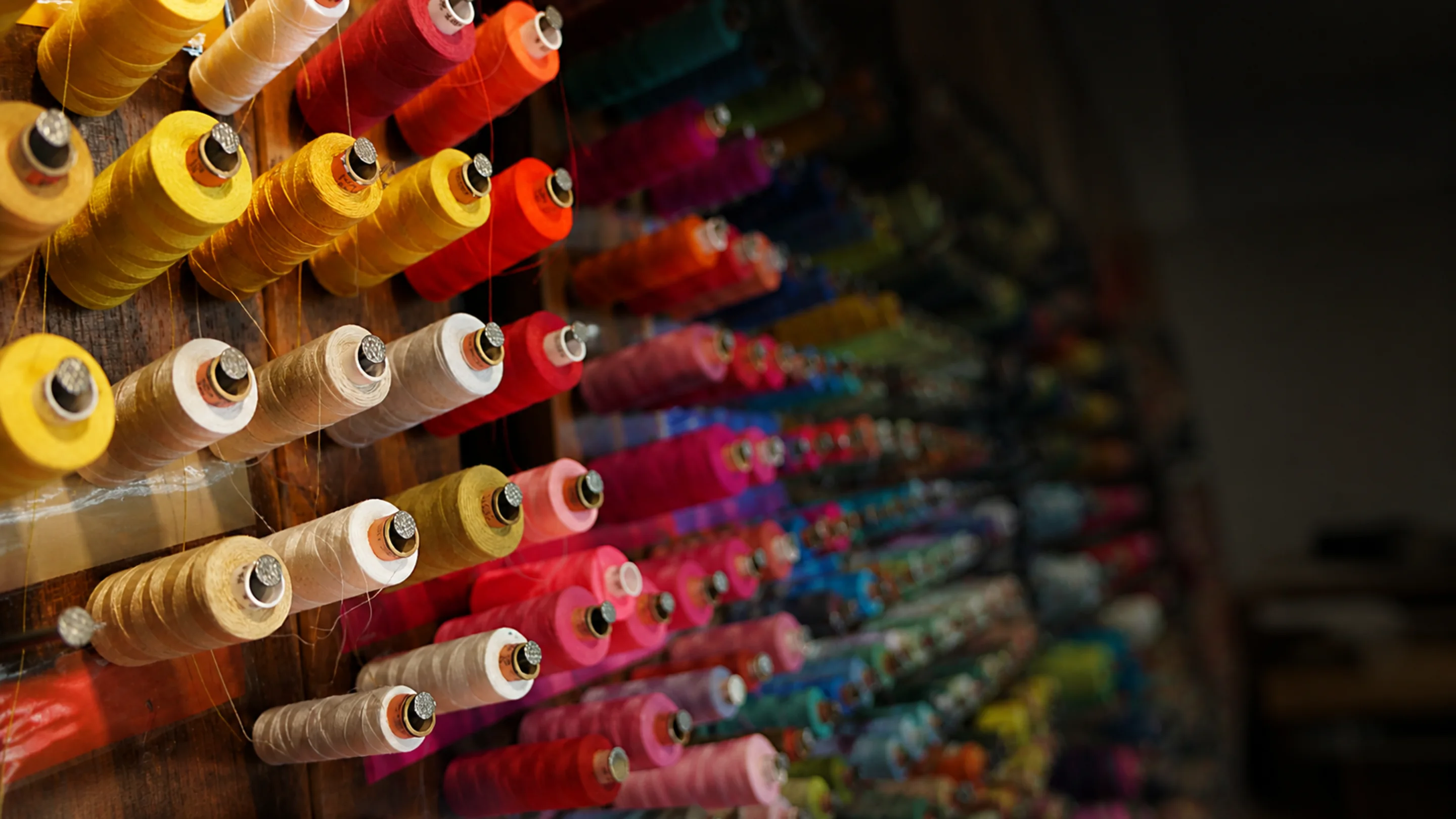Colorful thread spools racked in rows at a cycling apparel workshop