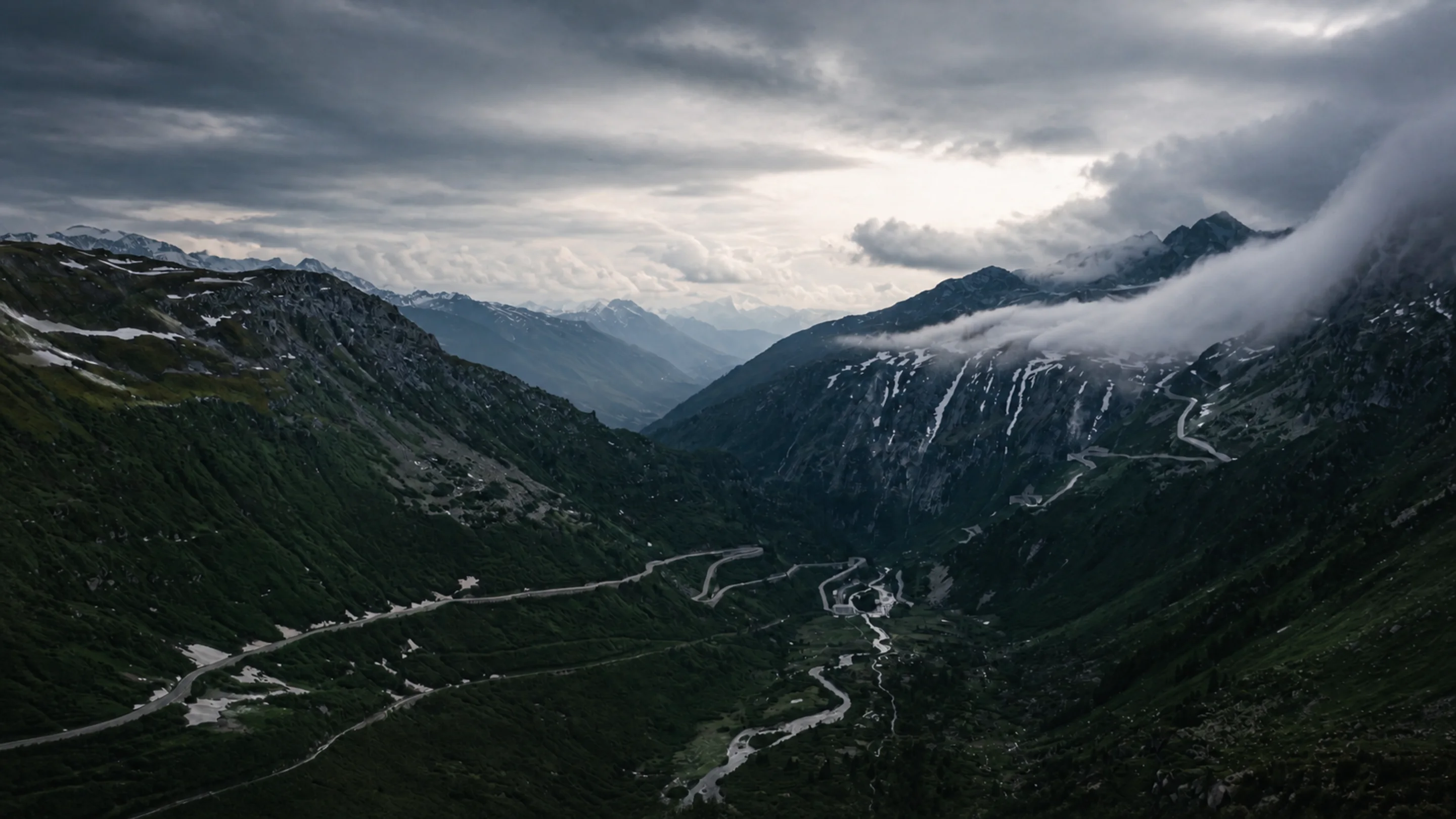 A remote mountain pass road winding through a wide alpine valley