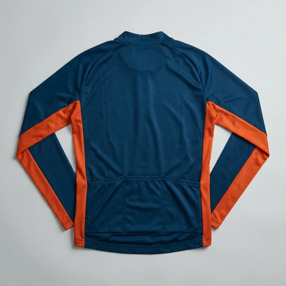 Back of a navy long-sleeve gravel jersey laid flat, orange side panels running from cuff to hem