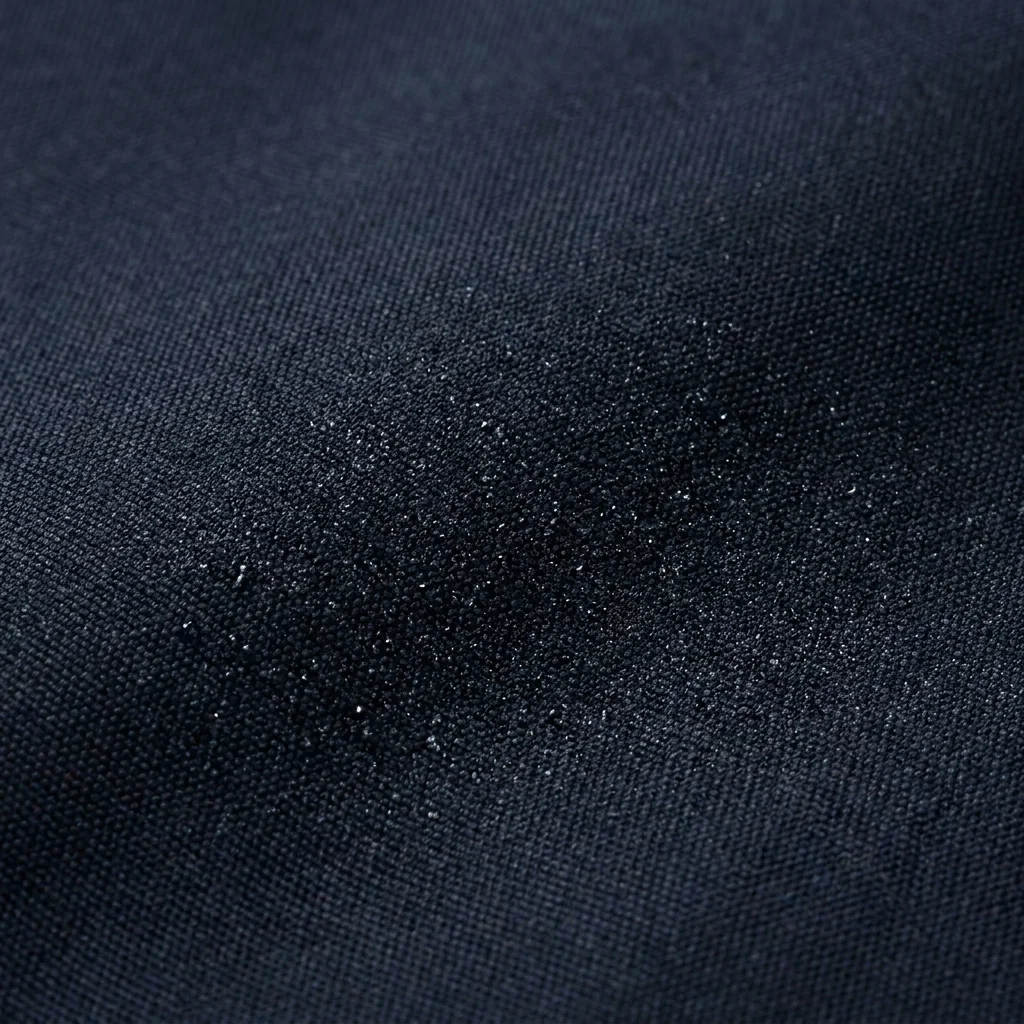 Fine dark shell fabric catching light across its surface