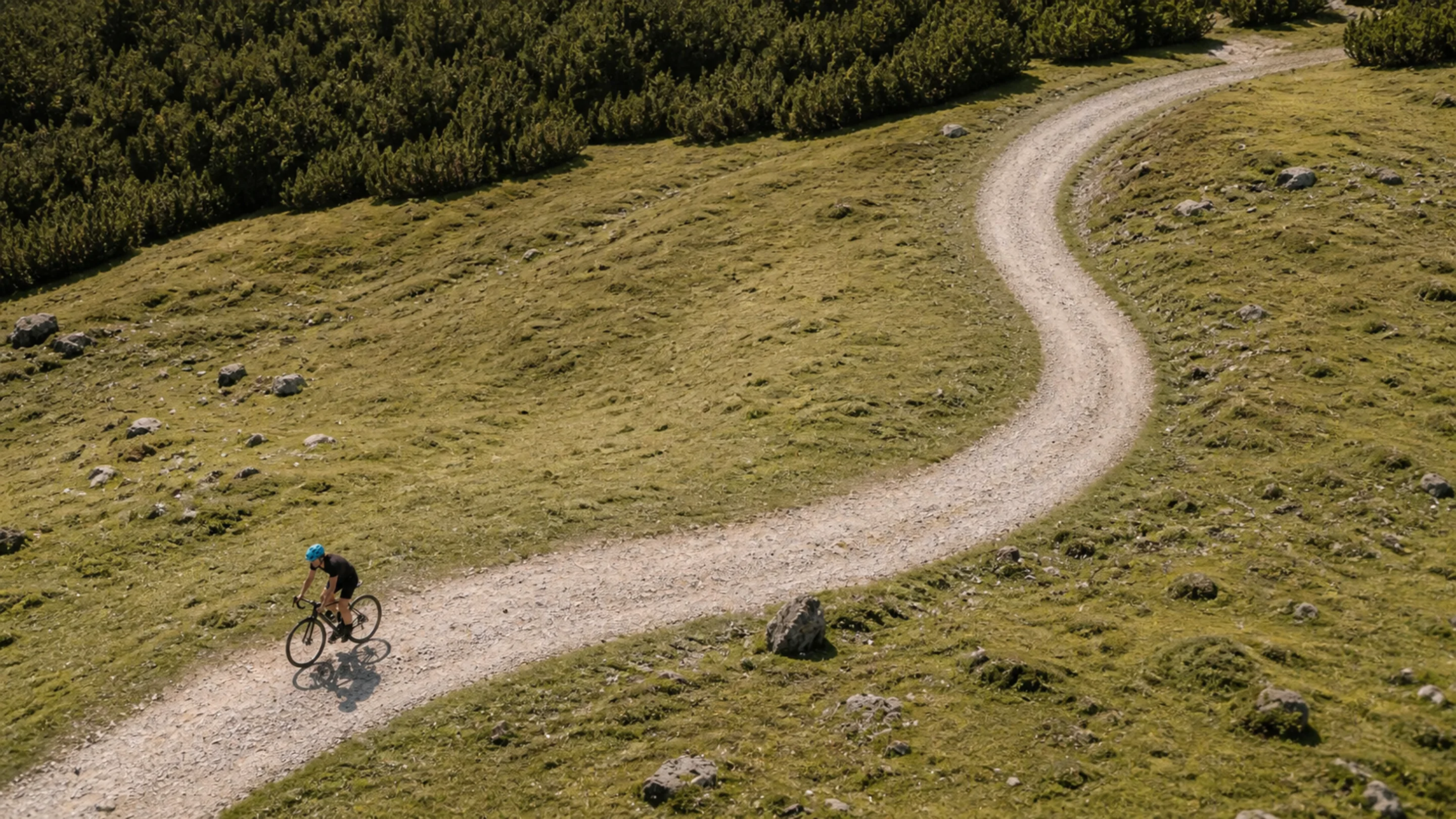 Aerial view of a cyclist riding a gravel path winding through grassy hills