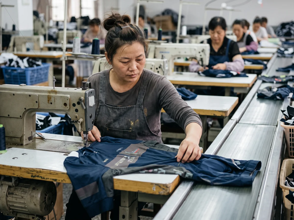 Operator checking garments at a machine on a running line