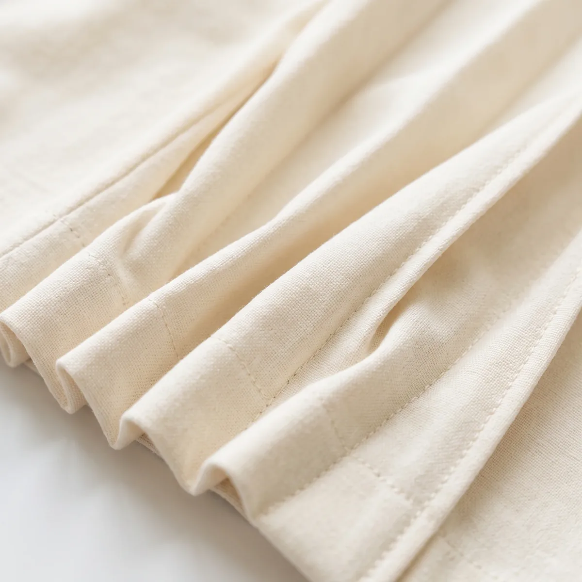 Cream fabric folded into soft diagonal pleats
