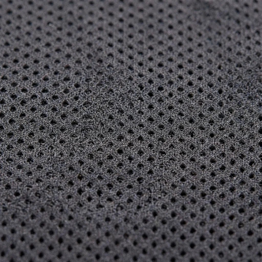 Close-up macro texture of mesh cycling fabric showing open honeycomb ventilation holes